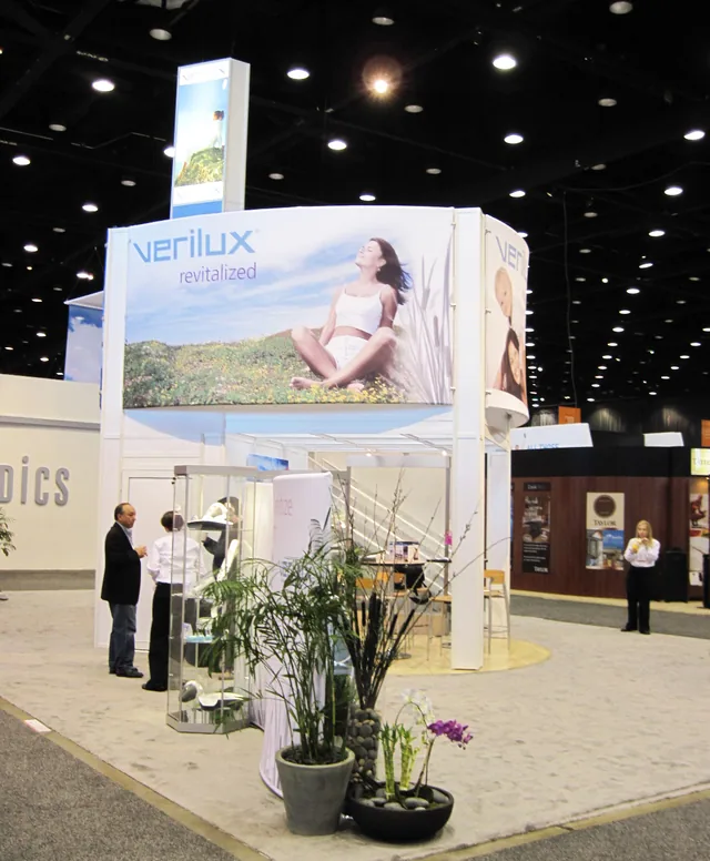 Photo of the Verilux trade show booth with a large Verilux revitalized banner above the exhibit floor.